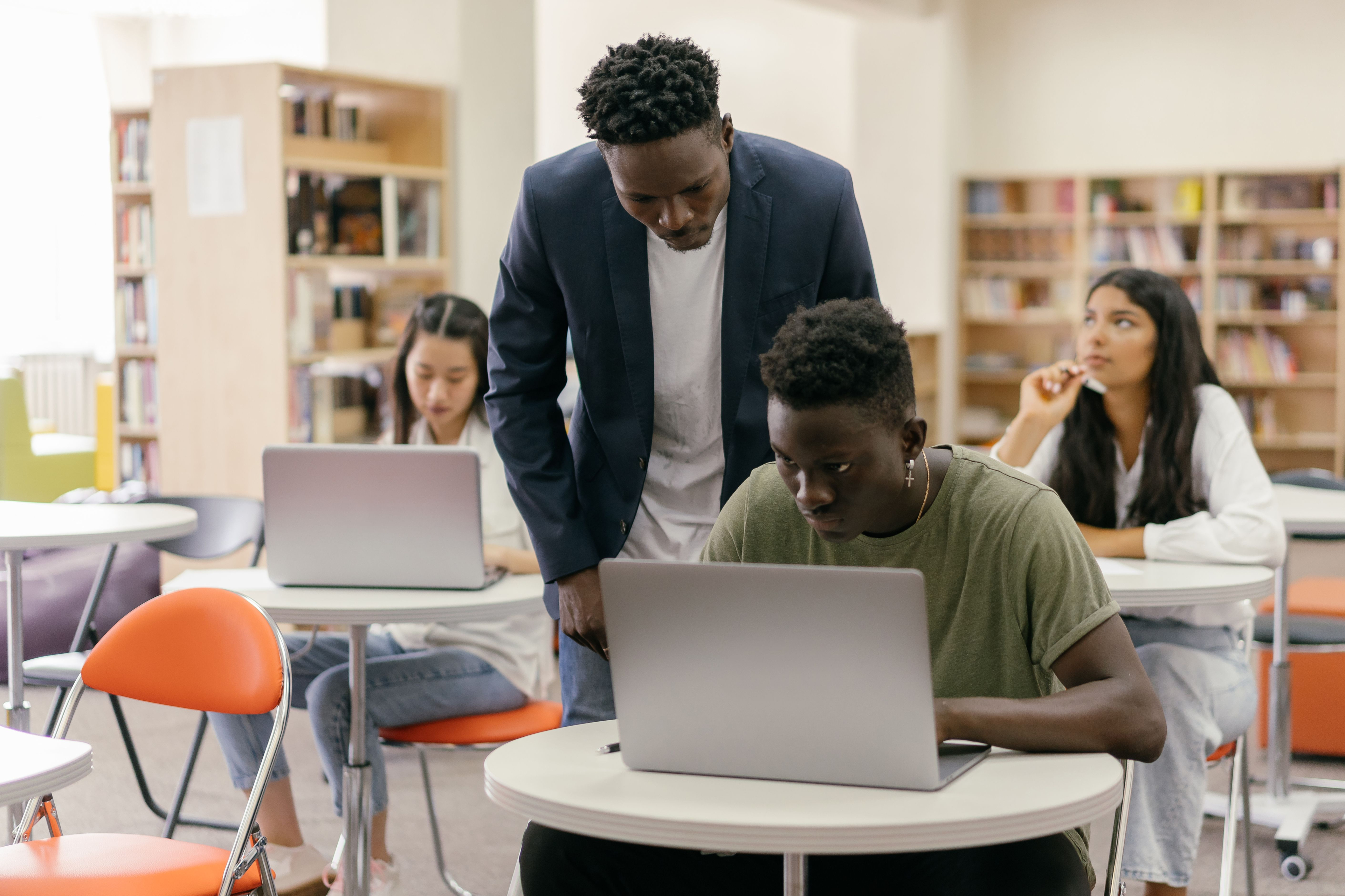 Mentor supporting students during a laptop workshop